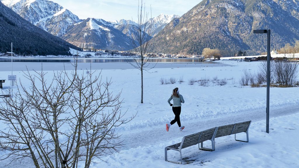 Eine LĂ€uferin im Winter am Ufer des Achensees.
